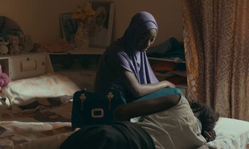 Movie still from “Atlantics” (2019), directed by Mati Diop – A woman sitting on a bed next to a man; Medium shot, High angle