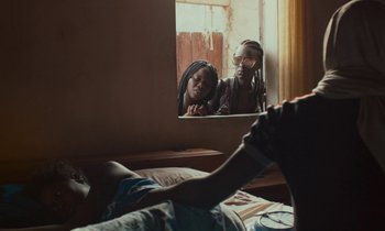 Movie still from “Atlantics” (2019), directed by Mati Diop – Two people are looking in a mirror in a bedroom; Medium shot, Over the shoulder angle