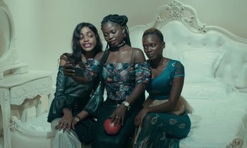 Movie still from “Atlantics” (2019), directed by Mati Diop – A group of three young women posing for a picture; Medium shot, Low angle