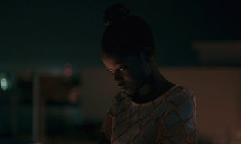 Movie still from “Atlantics” (2019), directed by Mati Diop – A young woman is standing in a dark room; Close Up shot, Over the shoulder angle