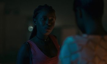 Movie still from “Atlantics” (2019), directed by Mati Diop – A woman in a red dress standing next to a man in a black shirt; Close Up shot, Over the shoulder angle