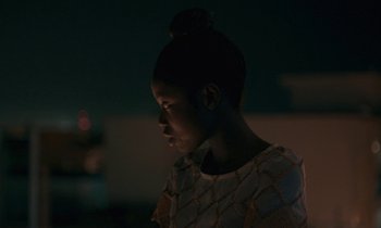 Movie still from “Atlantics” (2019), directed by Mati Diop – A young girl is looking into the distance; Close Up shot, Over the shoulder angle