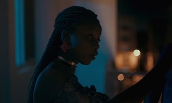 Movie still from “Atlantics” (2019), directed by Mati Diop – A young woman with braids is looking into the distance; Close Up shot, Over the shoulder angle