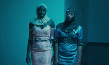 Movie still from “Atlantics” (2019), directed by Mati Diop – Two young women standing next to each other in a room; Medium shot, Low angle