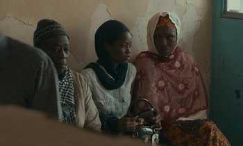 Movie still from “Atlantics” (2019), directed by Mati Diop – A group of women sitting next to each other; Medium shot, Over the shoulder angle