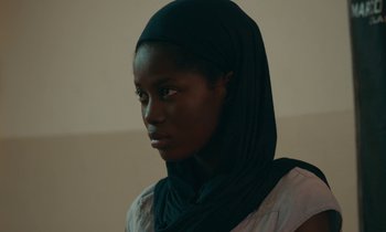 Movie still from “Atlantics” (2019), directed by Mati Diop – A woman wearing a head scarf is looking into the distance; Close Up shot, Over the shoulder angle