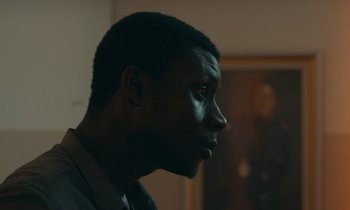 Movie still from “Atlantics” (2019), directed by Mati Diop – A person looking to his left; Close Up shot, Low angle