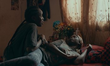 Movie still from “Atlantics” (2019), directed by Mati Diop – A couple of people that are sitting on a bed; Medium shot, Over the shoulder angle