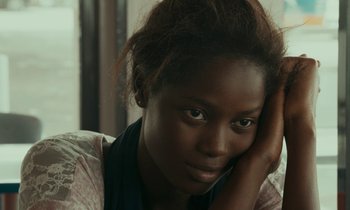 Movie still from “Atlantics” (2019), directed by Mati Diop – A person sitting down with her head resting on her hand; Close Up shot, High angle
