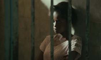 Movie still from “Atlantics” (2019), directed by Mati Diop – A young woman sitting in a jail cell; Close Up shot, High angle
