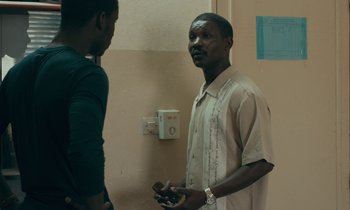 Movie still from “Atlantics” (2019), directed by Mati Diop – Two men standing next to each other in front of a wall; Medium shot, Over the shoulder angle