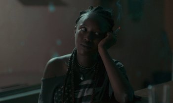Movie still from “Atlantics” (2019), directed by Mati Diop – A woman sitting in a dark room with a cigarette in her mouth; Close Up shot, Over the shoulder angle