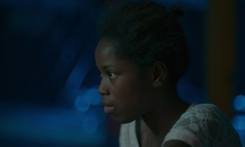Movie still from “Atlantics” (2019), directed by Mati Diop – A young black woman looking into the distance; Close Up shot, Over the shoulder angle