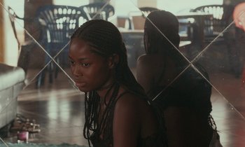Movie still from “Atlantics” (2019), directed by Mati Diop – A young woman with long braids looking into a mirror; Close Up shot, Over the shoulder angle