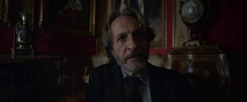Movie still from “Bardo: False Chronicle of a Handful of Truths” (2022), directed by Alejandro G. Iñárritu – A person wearing a suit and tie; Close Up shot, Low angle