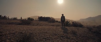 Movie still from “Bardo: False Chronicle of a Handful of Truths” (2022), directed by Alejandro G. Iñárritu – A group of people standing on top of a dry grass field; Extreme Wide shot, Low angle