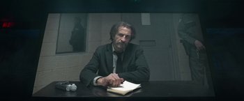 Movie still from “Bardo: False Chronicle of a Handful of Truths” (2022), directed by Alejandro G. Iñárritu – A man sitting at a table with a book in front of him; Medium shot, Low angle