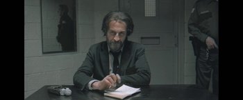 Movie still from “Bardo: False Chronicle of a Handful of Truths” (2022), directed by Alejandro G. Iñárritu – A man sitting at a table writing on a notebook; Medium shot, Low angle