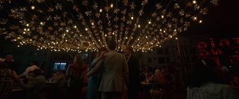 Movie still from “Bardo: False Chronicle of a Handful of Truths” (2022), directed by Alejandro G. Iñárritu – A group of people standing under lights in a room; Wide shot, Low angle