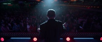 Movie still from “Bardo: False Chronicle of a Handful of Truths” (2022), directed by Alejandro G. Iñárritu – A man standing in front of an audience at a concert; Wide shot, High angle