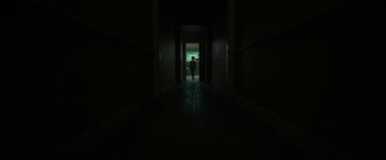 Movie still from “Bardo: False Chronicle of a Handful of Truths” (2022), directed by Alejandro G. Iñárritu – A person walking down a dark hallway at night; Extreme Wide shot, Low angle