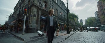 Movie still from “Bardo: False Chronicle of a Handful of Truths” (2022), directed by Alejandro G. Iñárritu – A man walking down a street with a skateboard; Wide shot, Low angle