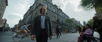 Movie still from “Bardo: False Chronicle of a Handful of Truths” (2022), directed by Alejandro G. Iñárritu – A man walking down the street in front of a building; Wide shot, Low angle