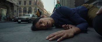 Movie still from “Bardo: False Chronicle of a Handful of Truths” (2022), directed by Alejandro G. Iñárritu – A person laying on the ground on the street; Medium shot, Overhead angle