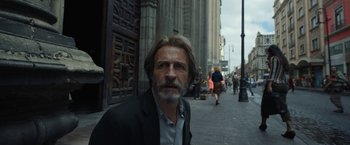 Movie still from “Bardo: False Chronicle of a Handful of Truths” (2022), directed by Alejandro G. Iñárritu – A person wearing a suit on a city street; Medium shot, Low angle