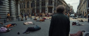Movie still from “Bardo: False Chronicle of a Handful of Truths” (2022), directed by Alejandro G. Iñárritu – A group of people laying on the ground in the middle of the street; Wide shot, High angle