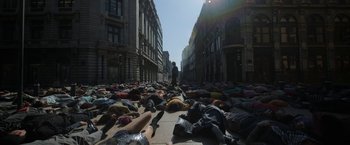 Movie still from “Bardo: False Chronicle of a Handful of Truths” (2022), directed by Alejandro G. Iñárritu – A group of people laying on the ground in the middle of the street; Extreme Wide shot, High angle
