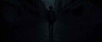 Movie still from “Bardo: False Chronicle of a Handful of Truths” (2022), directed by Alejandro G. Iñárritu – A man is walking down the street in the dark; Wide shot, Low angle