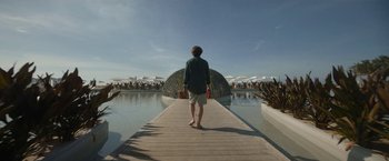 Movie still from “Bardo: False Chronicle of a Handful of Truths” (2022), directed by Alejandro G. Iñárritu – A man standing on a pier in front of a body of water; Wide shot, Low angle