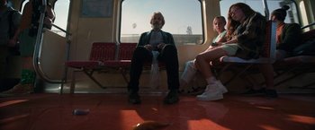 Movie still from “Bardo: False Chronicle of a Handful of Truths” (2022), directed by Alejandro G. Iñárritu – A man sitting on a bench next to a woman on a train; Wide shot, Low angle