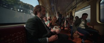 Movie still from “Bardo: False Chronicle of a Handful of Truths” (2022), directed by Alejandro G. Iñárritu – A group of people riding on a train together; Wide shot, Over the shoulder angle