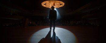 Movie still from “Bardo: False Chronicle of a Handful of Truths” (2022), directed by Alejandro G. Iñárritu – A man standing on a stage in front of an audience; Wide shot, Low angle