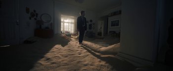 Movie still from “Bardo: False Chronicle of a Handful of Truths” (2022), directed by Alejandro G. Iñárritu – A man in a suit and tie standing in the middle of a living room; Extreme Wide shot, High angle