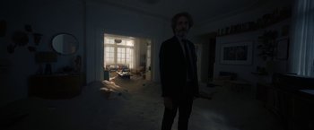 Movie still from “Bardo: False Chronicle of a Handful of Truths” (2022), directed by Alejandro G. Iñárritu – A man in a suit and tie standing in a living room; Wide shot, Low angle