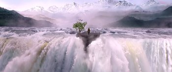 A man standing on top of an island in the middle of a waterfall