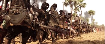 Movie still from “Baahubali: The Beginning” (2015), directed by S.S. Rajamouli – A group of men in costume holding swords and a spear; Wide shot, Low angle