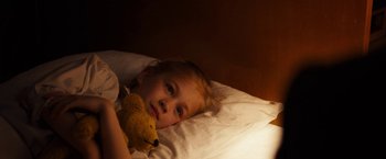 Movie still from “The Resistance Banker” (2018), directed by Joram Lürsen – A little girl laying in a bed with a teddy bear; Close Up shot, High angle