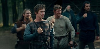 Movie still from “Barbarians” (2020), created by Arne Nolting – A group of men standing next to each other on a field; Medium shot, Low angle