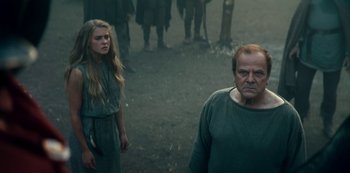 Movie still from “Barbarians” (2020), created by Arne Nolting – A man and a woman standing next to each other in a field; Medium shot, Low angle