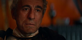 Movie still from “Barbarians” (2020), created by Arne Nolting – An older man wearing a neck tie looking at the camera; Close Up shot, Over the shoulder angle