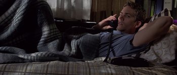 A man laying in bed talking on a phone