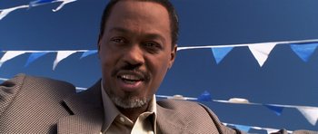 Movie still from “Joy Ride” (2001), directed by John Dahl – A person wearing a suit and smiling; Close Up shot, Low angle