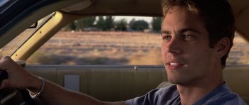 Movie still from “Joy Ride” (2001), directed by John Dahl – A man driving a car in the middle of a field; Close Up shot, Over the shoulder angle