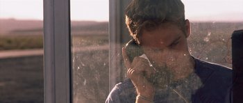 A woman is talking on a cell phone by a window