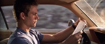 Movie still from “Joy Ride” (2001), directed by John Dahl – A young man driving a car in the day time; Close Up shot, Over the shoulder angle