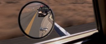 Movie still from “Joy Ride” (2001), directed by John Dahl – A police car is reflected in the side mirror of a car; Close Up shot, Low angle